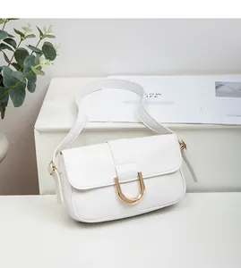 Detail of white leather shoulder bag with golden horseshoe buckle and adjustable strap