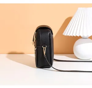 Detailed side view of black crossbody phone bag featuring floral embroidery and gold zipper
