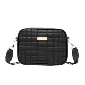 Quilted black crossbody bag with gold metal plaque and wide adjustable woven strap