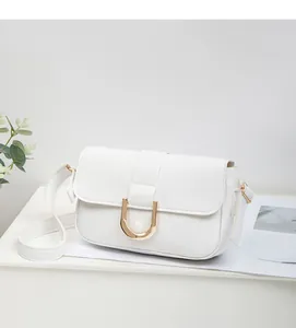 Close-up of white crossbody bag with textured leather and gold horseshoe metal buckle