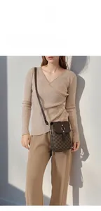 Detail of a brown monogram crossbody bag with golden buckle and adjustable strap