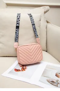 Detail of pink quilted crossbody bag with stylish contrast lettering shoulder strap