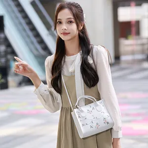White embroidered floral handbag with long strap shown in a lifestyle outdoor setting