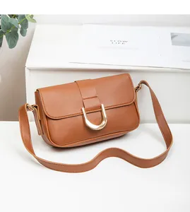 Close-up of brown leather shoulder bag featuring a vintage golden horseshoe buckle detail