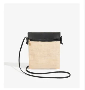 Close-up of straw woven texture and black leather trim on minimalist crossbody phone bag