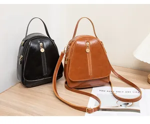Détail de mini sacs à dos en cuir PU noir et marron posés sur une table en bois