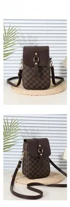Detail of crossbody phone bag with monogram pattern and golden metal hardware
