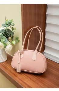 Detail der rosa Kieselleder-Textur und des modischen Anhängers an der minimalistischen Tasche