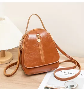 Détail d'un mini sac à dos en cuir marron avec fermetures éclair dorées posé sur une table