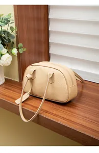 Nahaufnahme der beigen Handtasche aus Leder mit Knoten-Henkel und modischem Anhänger