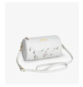 Détails du sac cylindrique blanc avec broderies florales et finitions dorées chic