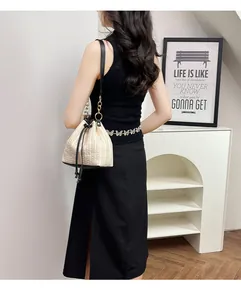 Vue portée d'un sac seau en paille avec base en cuir noir et chaîne dorée