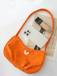 Makroaufnahme der orangefarbenen PU-Lederstruktur und Schmetterlingsdetail der Tasche