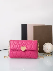 Detail of rose pink heart quilted handbag with gold heart lock and chain strap