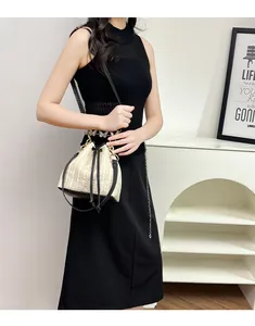 Détail du sac seau en paille beige avec bordure en cuir noir et chaîne dorée chic
