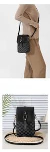 Detail of trendy crossbody phone bag with M-letter print and adjustable shoulder strap