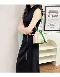Détail du sac seau en paille beige avec bordure en cuir vert et bandoulière chaîne