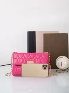 Rose pink heart quilted chain bag shown with a smartphone for size scale comparison