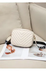 Detail of cream quilted crossbody bag with V-shaped stitching and BAG.T jacquard strap