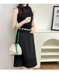 Détail du sac seau en paille tissée avec cordon vert et chaîne papillon en métal chic