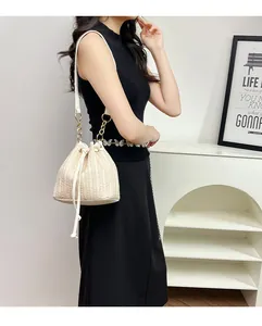 Détail du sac seau tissé beige avec fermeture à cordon et chaîne en métal doré élégante