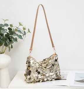 Close-up of shiny gold sequin texture and leather strap on women's shoulder bag