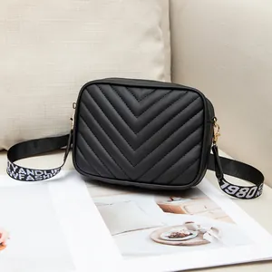 Minimalist black quilted crossbody bag with stylish FASHION wide lettered strap on sofa