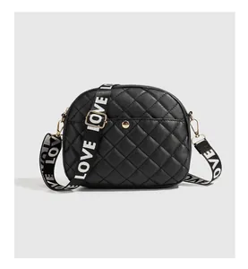 Detail of black quilted crossbody bag with a wide LOVE lettered woven strap and gold hardware