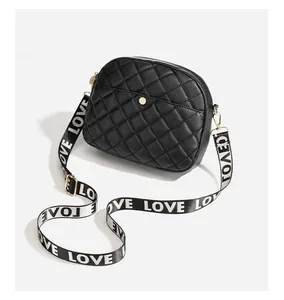 Detail of black quilted crossbody bag featuring a golden snap button and LOVE printed strap