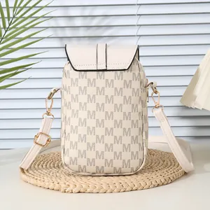 Chic cream small crossbody phone bag with M-letter prints on a woven mat with green leaf