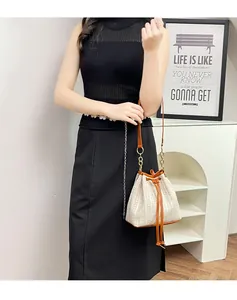 Détails du sac seau en paille crème avec bordure en cuir marron et cordon de serrage