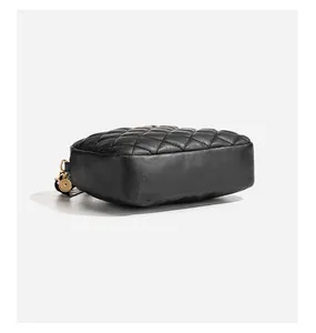 Detail of black quilted leather camera bag featuring golden metal rings and smooth sides