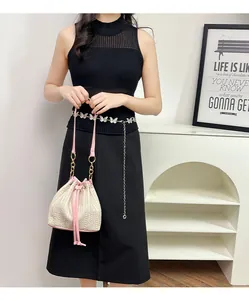 Détail du sac seau tissé avec bordure en cuir rose et chaîne en métal élégante