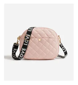 Close-up of pink quilted crossbody bag with gold buckle and LOVE letter wide strap
