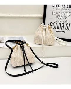 Détail de sacs seaux en paille tressée avec cordon de serrage et chaînes dorées