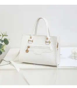 Details einer weißen Handtasche mit Krokodilprägung, Goldteilen und Reißverschlusstasche