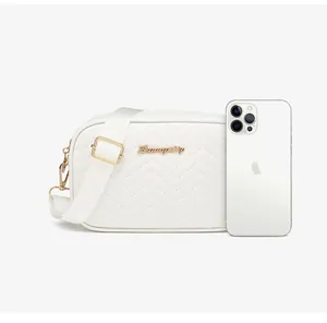 White quilted crossbody bag shown next to a smartphone to demonstrate the mini size