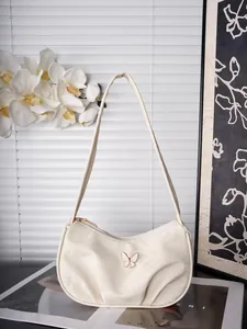 Nahaufnahme der cremeweißen Schultertasche mit eleganter Schmetterling-Metallschnalle