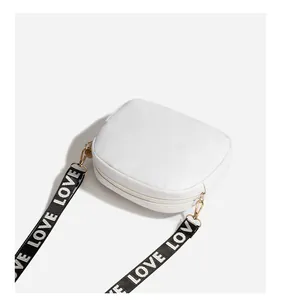 Detail of white quilted crossbody bag featuring a black and white LOVE woven shoulder strap