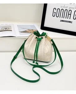 Détail d'un sac seau en paille tissée avec cordon en cuir vert et accents en métal doré