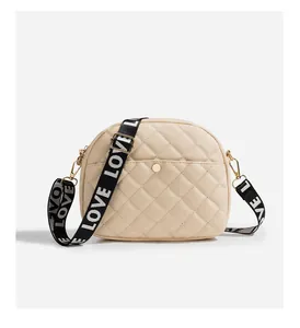 Detail of beige quilted camera bag with love strap and golden metal buckle
