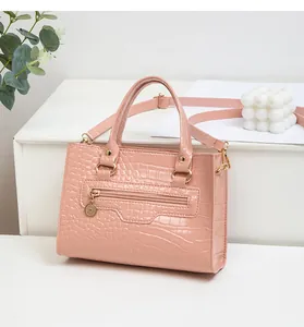 Detail der rosa Handtasche mit Krokodilprägung, glänzender Textur und Goldanhänger