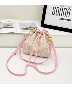 Détail du sac seau en paille avec cordon en cuir rose et chaîne en métal doré