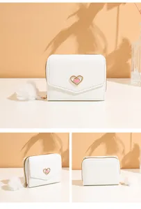 Detail of white tri-fold wallet with pink heart buckle and soft plush ball pendant