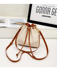 Détail du sac seau en paille avec cordon en cuir marron et coutures en dents de scie