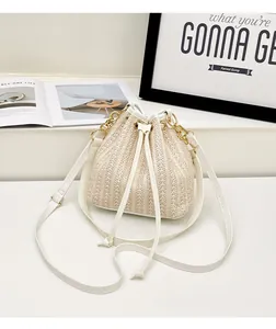 Détail du sac seau en paille avec fermeture à cordon et poignée en chaîne dorée chic