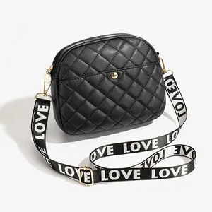 Black quilted crossbody camera bag with gold hardware and wide LOVE letter strap