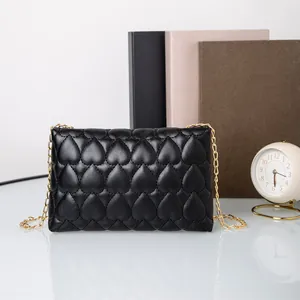 Black heart-quilted crossbody bag with gold chain strap for minimalist daily commute