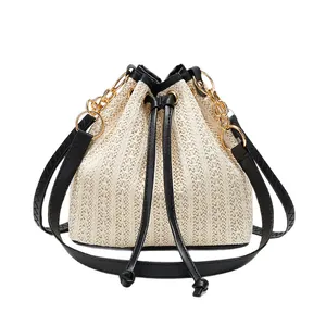 Sac seau minimaliste en paille pour femme avec garniture en cuir noir et bandoulière chaîne