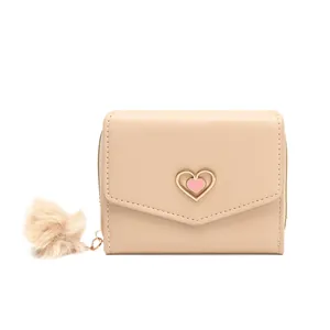Women's beige short tri-fold wallet with golden heart accent and fluffy pompom keychain